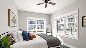 A bedroom with a bed, a ceiling fan, a window, and a view of a building outside. - Luxury Condo w/ Beach Access | Dragestil 717-1 (Duluth)