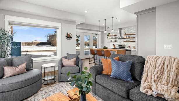 A modern living room with grey sofas, a coffee table, and a view of the backyard. - Luxury Condo w/ Beach Access | Dragestil 717-1 (Duluth)