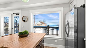 A modern kitchen with a wooden island, stainless steel refrigerator, and large windows overlooking a street. - Luxury Condo w/ Beach Access | Dragestil 717-2 (Duluth)