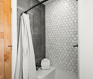 Un baño con cortina de ducha, una toalla y una botella de champú.