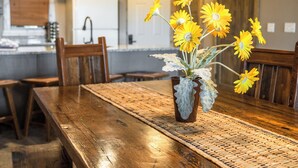 A dining table with a woven placemat, a vase with yellow flowers, and wooden chairs.
