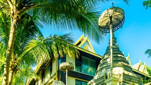 A traditional building with ornate architecture, including a large decorative umbrella and a bell tower. - Yun Guan Shunde Renjia Resort Hotel (Xishuangbanna Dai)
