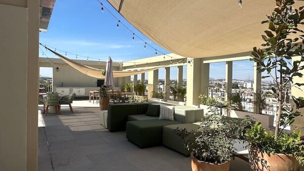 A rooftop terrace with outdoor seating, potted plants, and string lights.