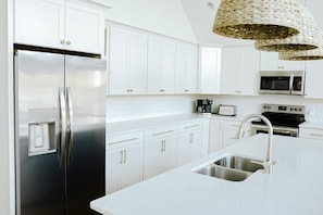 A modern kitchen with white cabinetry, stainless steel appliances, and a built-in sink.