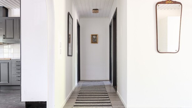 A hallway with a wooden floor, a striped rug, and framed pictures on the walls. - Skärvudde Villan by Interhome (Kalvsvik)