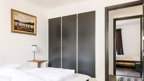 A bedroom with a large bed, a bedside table with a lamp, a wardrobe, and a door leading to another room. - Skärvudde Villan by Interhome (Kalvsvik)