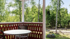 A covered outdoor seating area with a round table and chairs, surrounded by a wooden deck and a red heart-patterned fence. - Skärvudde Villan by Interhome (Kalvsvik)