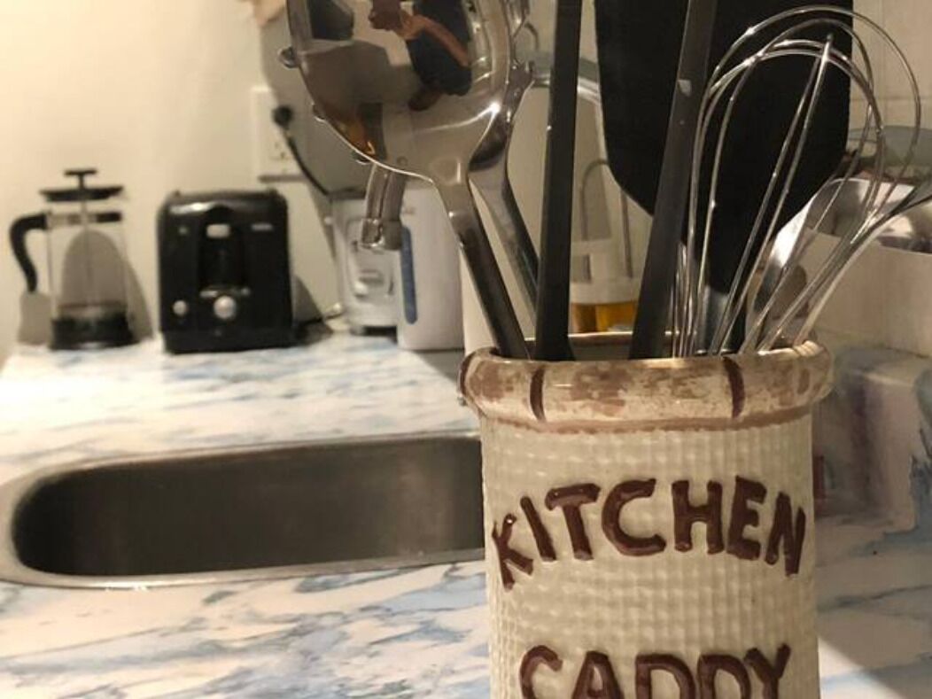 Ein Küchenzubehörhalter mit dem Aufdruck "KITCHEN CADDY" und verschiedenen Küchenutensilien darin.