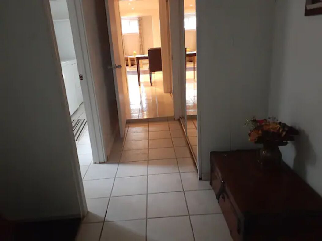 A hallway with a tiled floor leading to a room with a dining table and chairs.