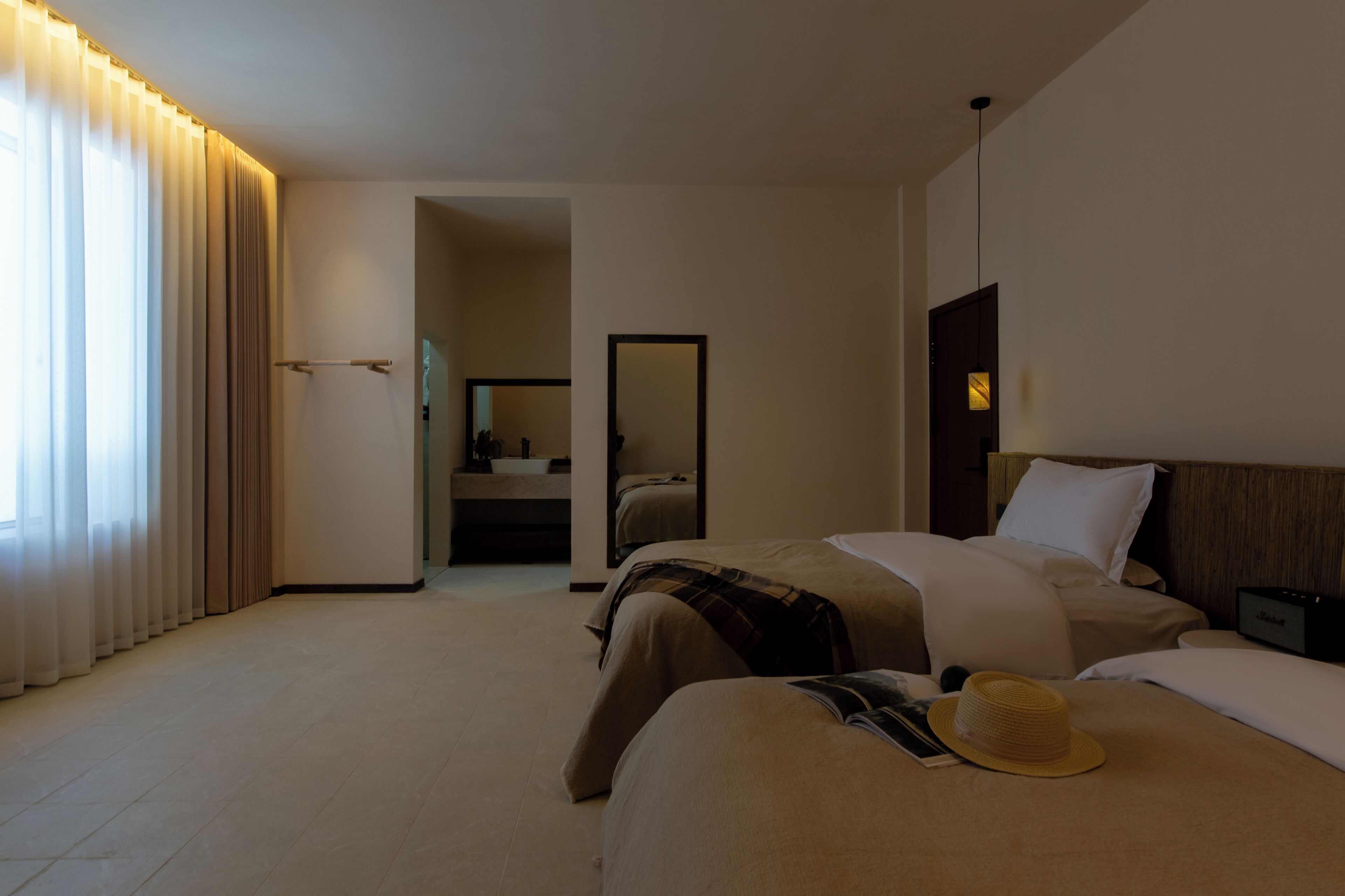 A hotel room with a bed, bedside table, and a window with curtains.