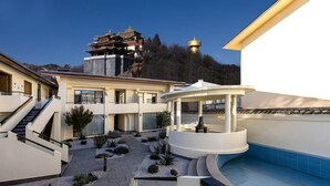 A modern building with a pool, a gazebo, and a traditional pagoda in the background. - Bandu Oxygen Supply Homestay (Deqin)