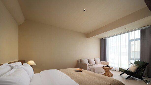 A hotel room with a large bed, a sofa, a chair, and a small table. - Bandu Oxygen Supply Homestay (Deqin)