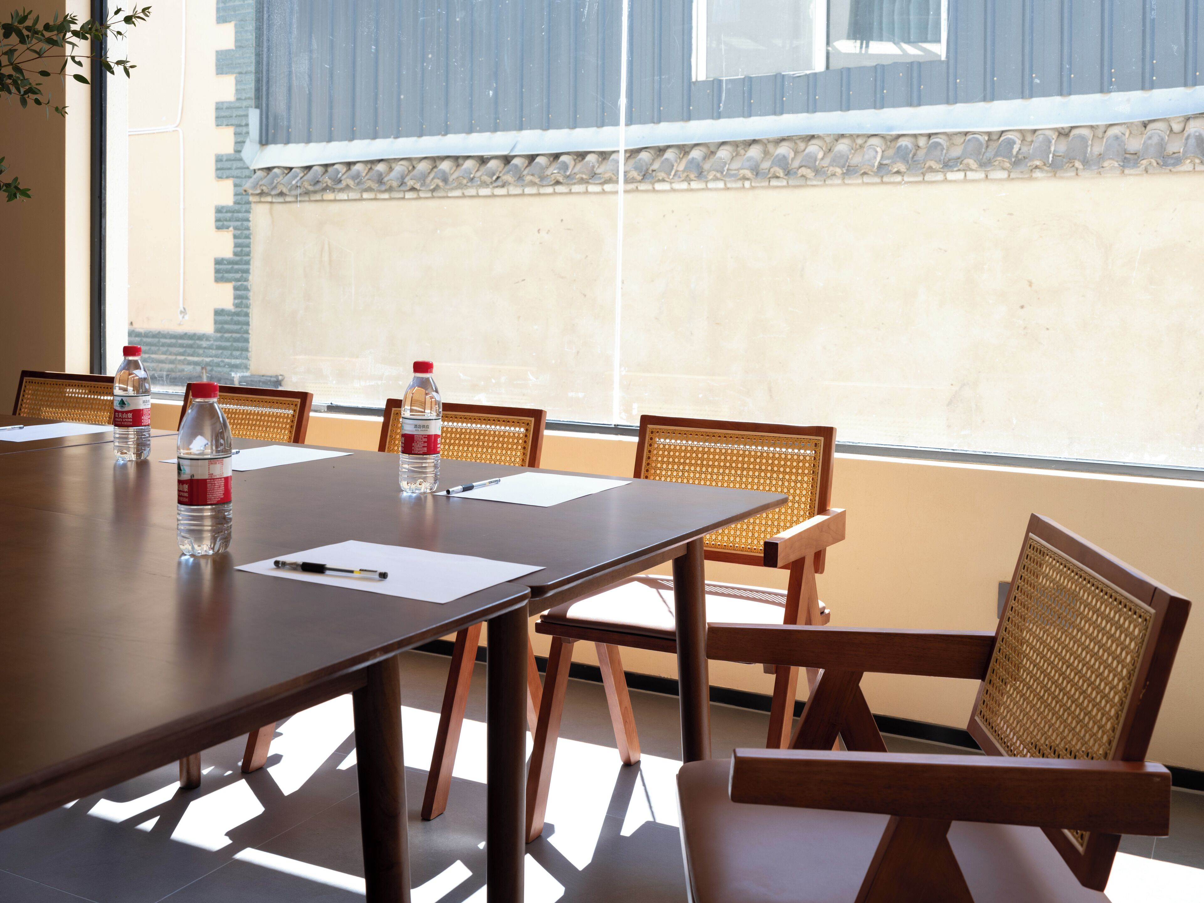 Una sala conferenze con un lungo tavolo, diverse sedie e due bottiglie d'acqua sul tavolo.