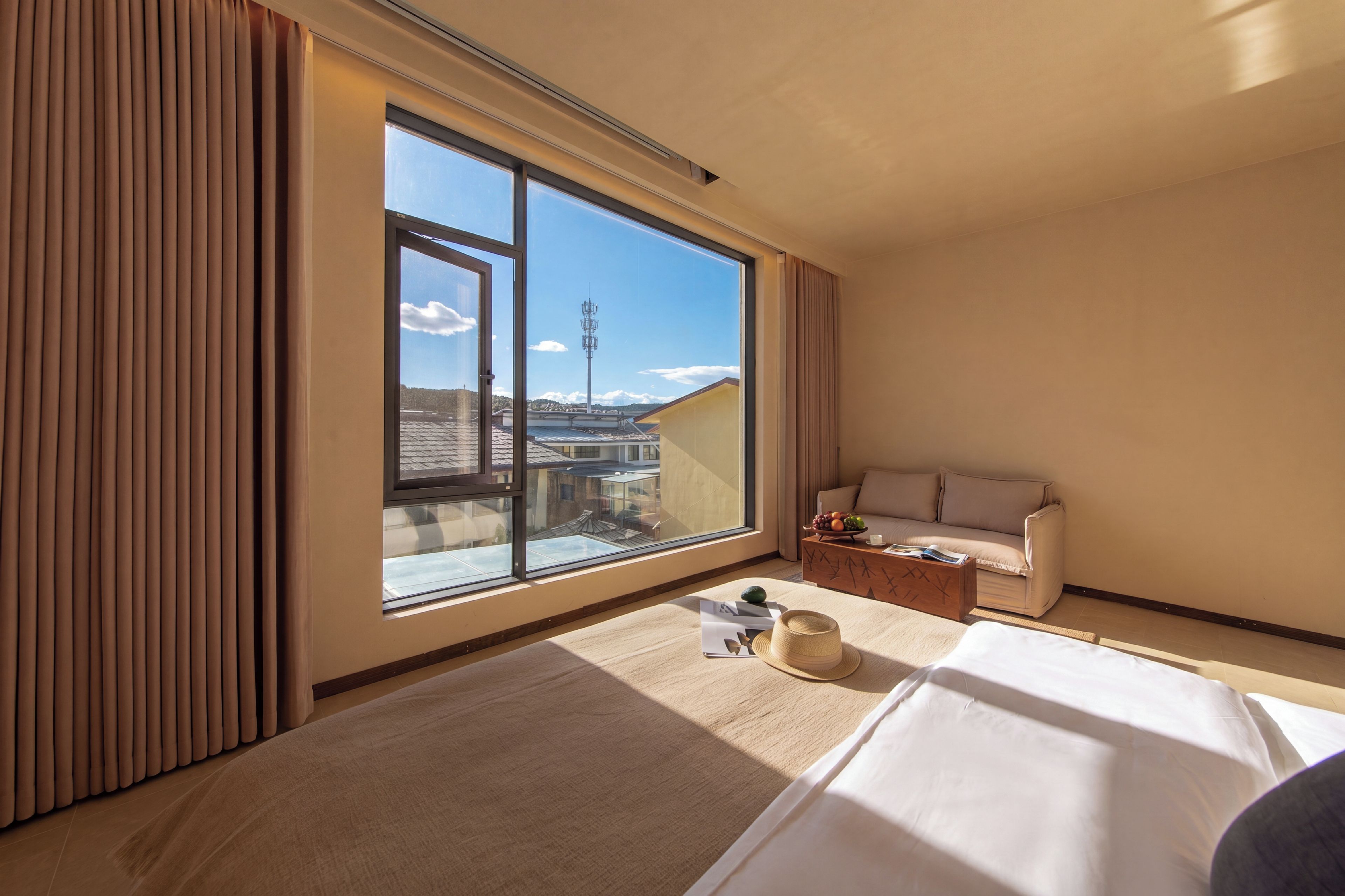 Una habitación de hotel con un ventanal grande, una cama, un sofá y una mesita de café.