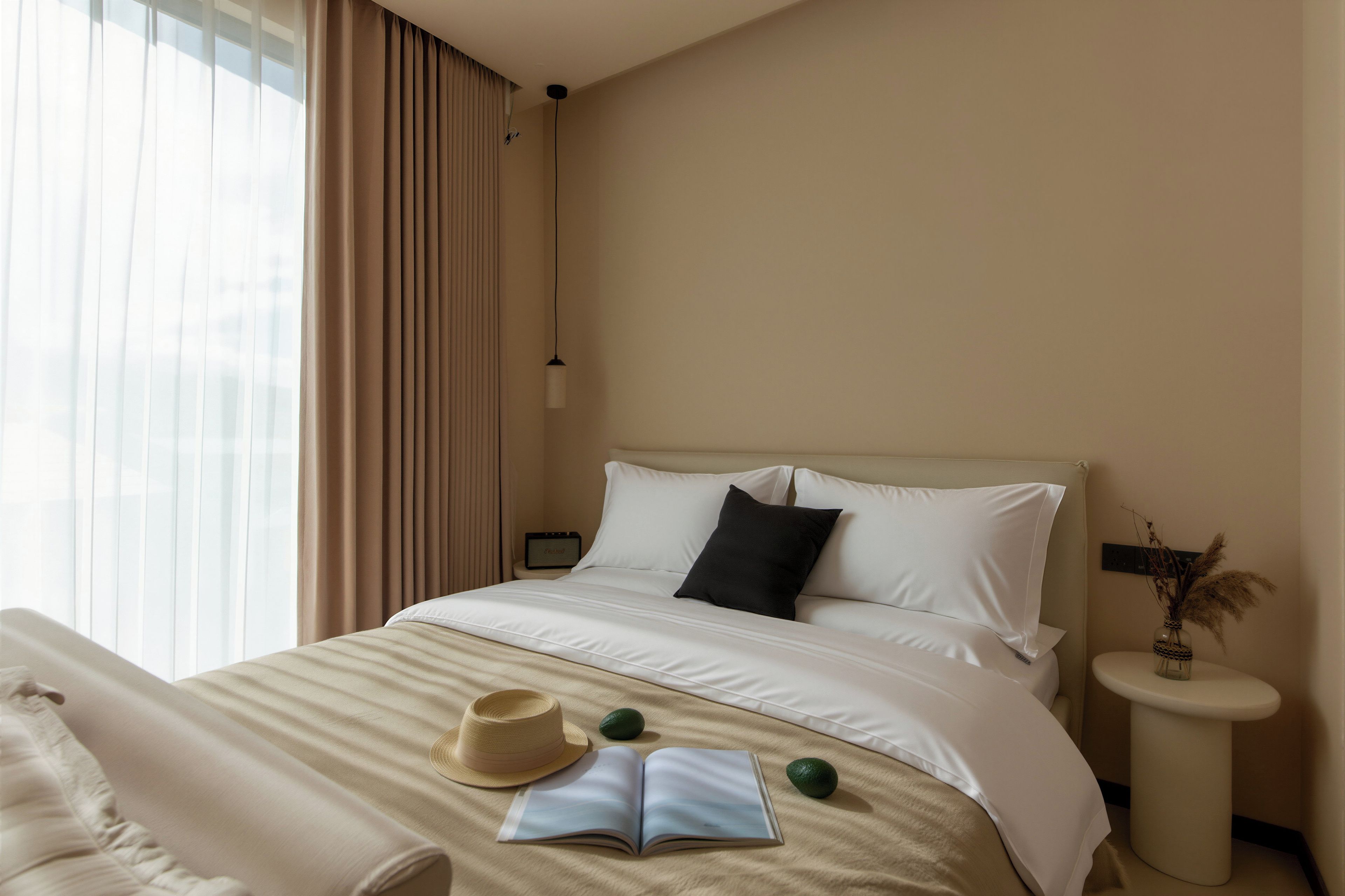 A hotel room with a bed, a nightstand, a lamp, a window with curtains, a chair, a hat, an open book, and a small plant.