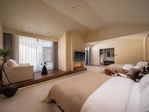 A hotel room with a large bed, a seating area with a table, a TV, and a bathroom with a sink and mirror. - Bandu Oxygen Supply Homestay (Deqin)