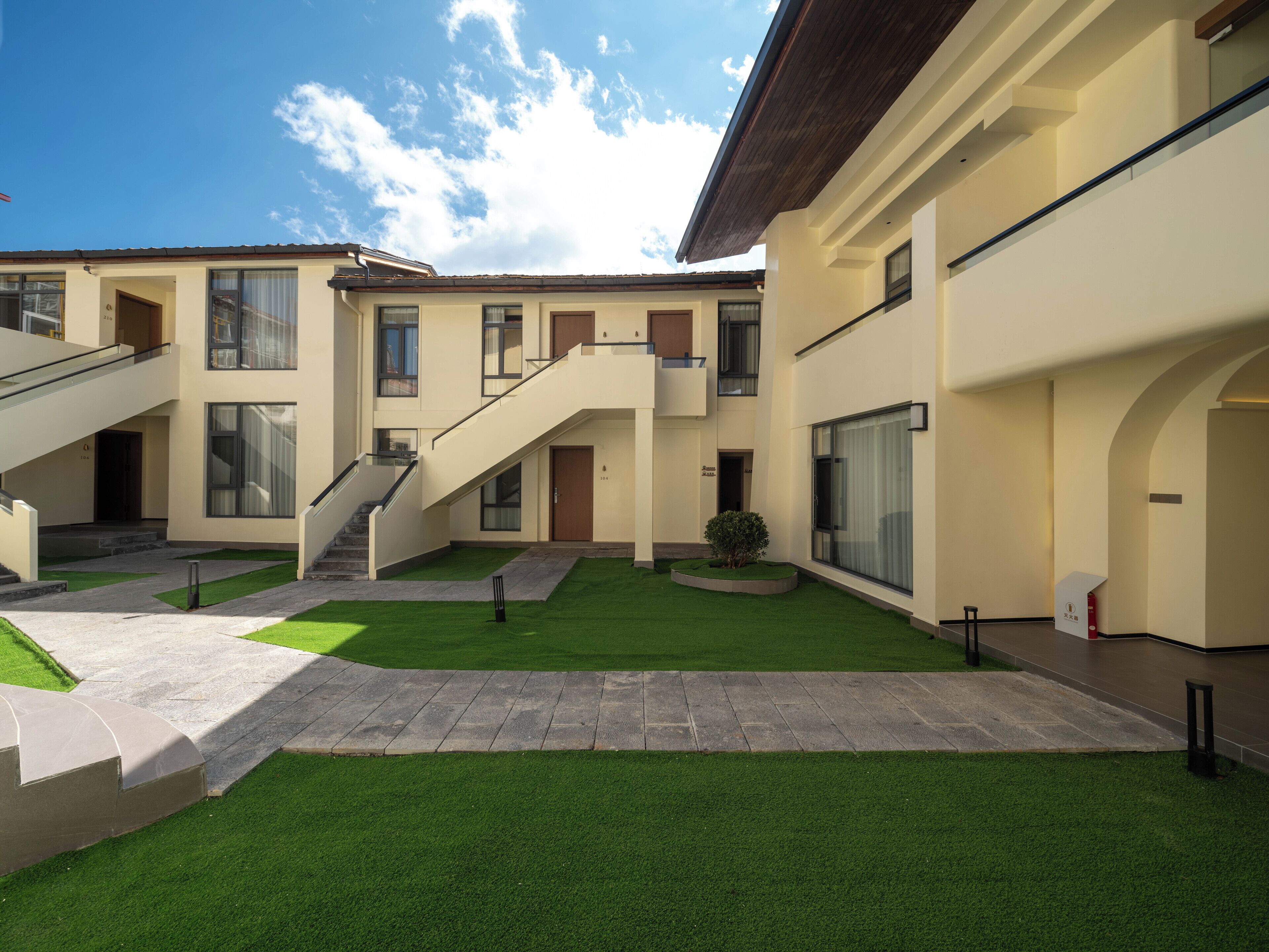 A modern building with a courtyard, featuring a central staircase, a small garden, and a flat roof.