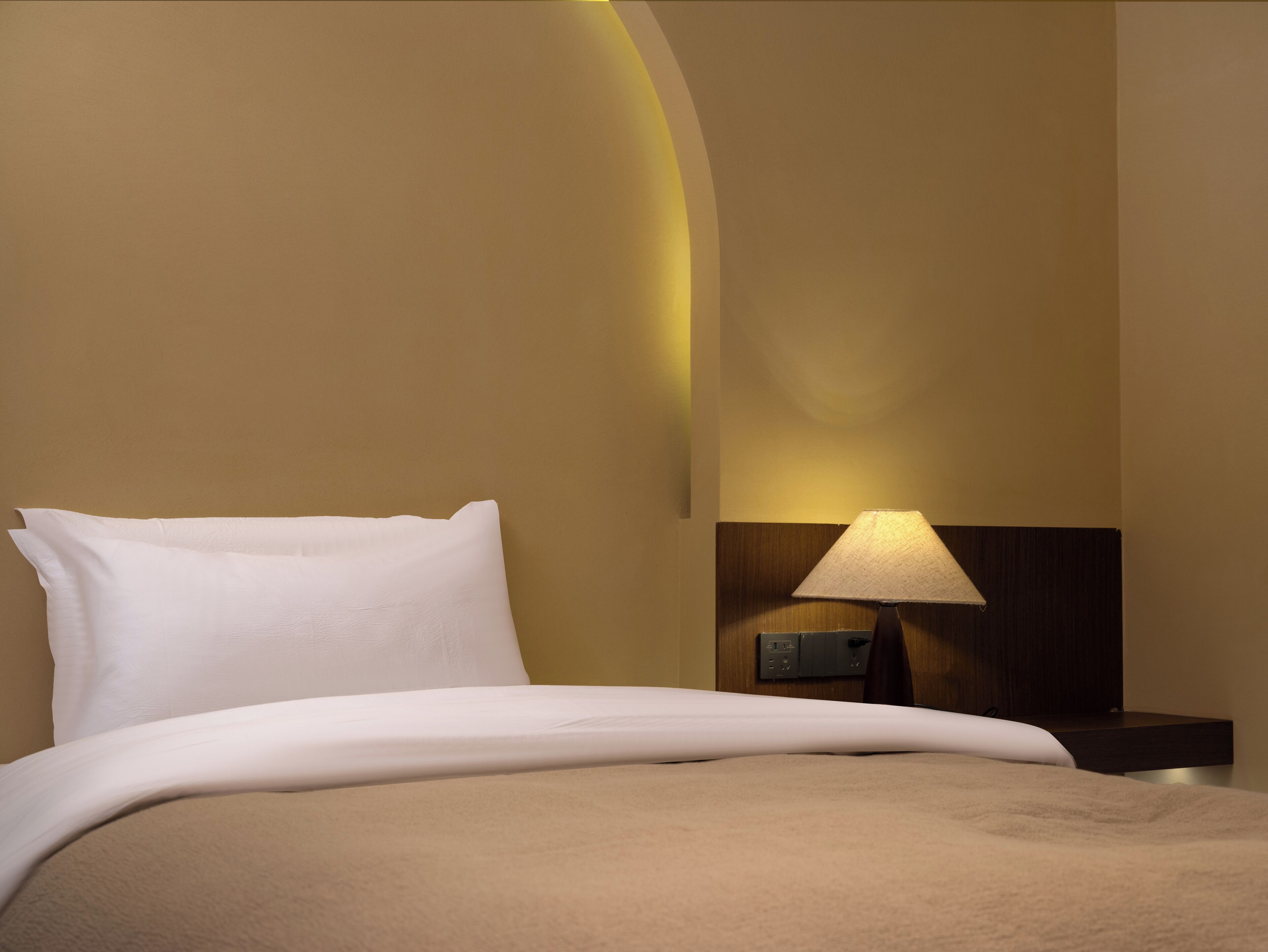 Une chambre d’hôtel avec un lit, une table de chevet et une lampe.