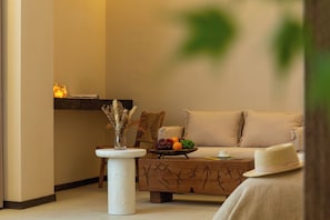 Ein gemütliches Wohnzimmer mit einer Couch, einem Couchtisch mit Früchten, einer Vase mit Trockenpflanzen und einem kleinen Beistelltisch.
