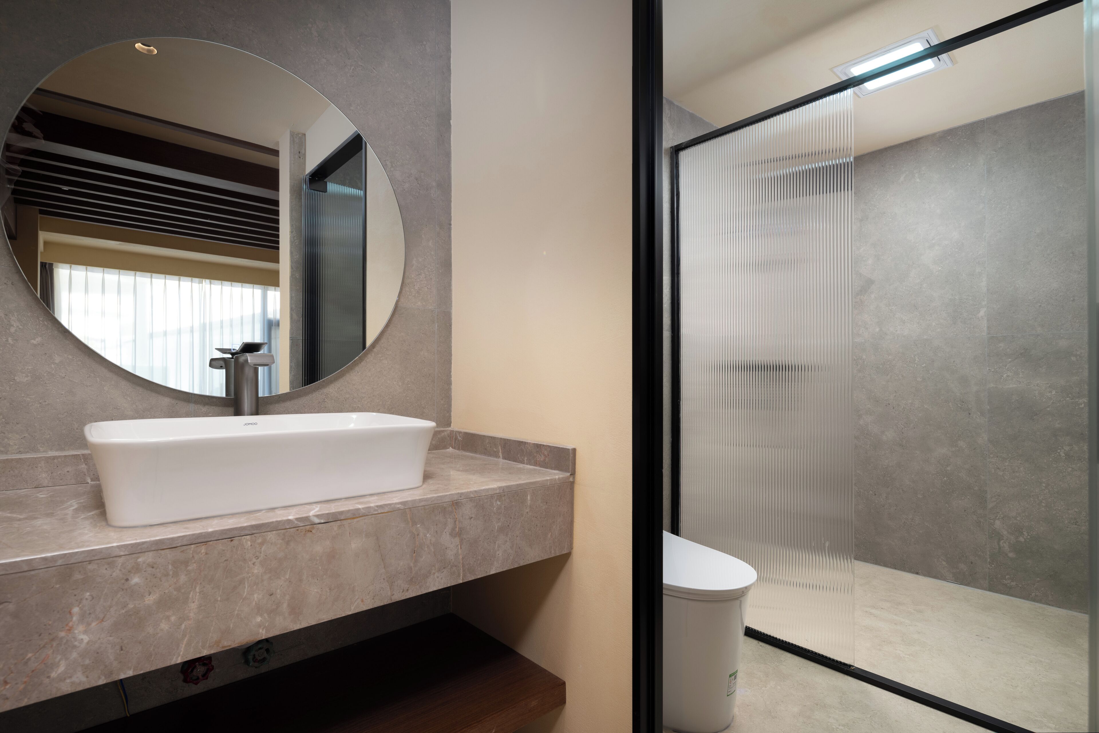 A bathroom with a modern design, featuring a large mirror, a rectangular sink, and a glass shower enclosure.