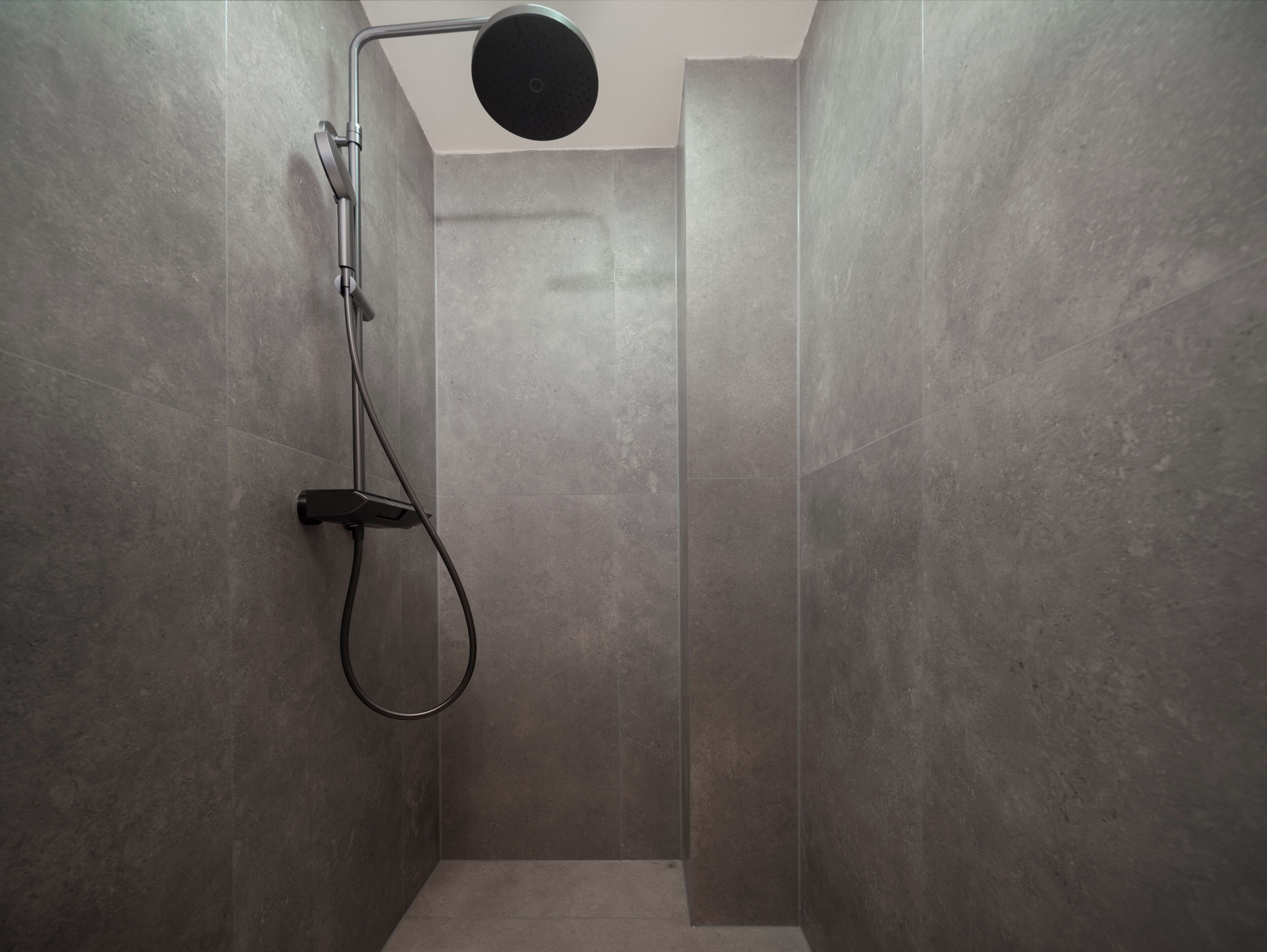 A modern shower with a handheld showerhead and a wall-mounted control panel.