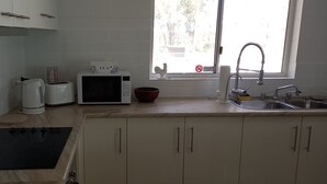 Een keuken met een magnetron, broodrooster, waterkoker en spoelbak.