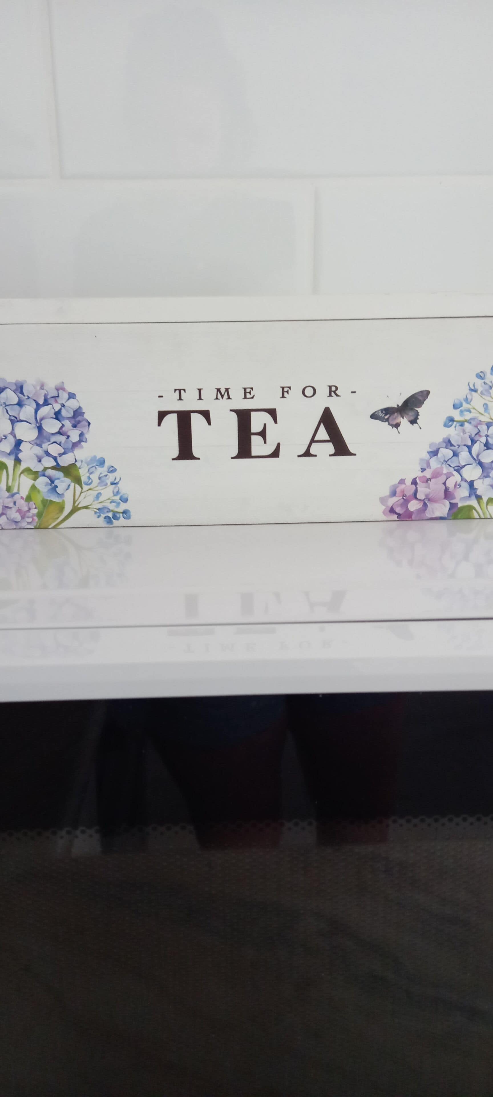 Un letrero con el texto 'TIME FOR TEA' rodeado de adornos florales.