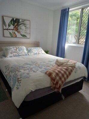A bedroom with a bed, a window with curtains, a wall-mounted painting, and a small potted plant. - Cosy Country Getaway Bungadoo.A/C 35 Minutes to Bundaberg. Self-contained& Quiet (Bungadoo)