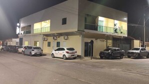 Ein zweistöckiges Gebäude mit flachem Dach, zahlreichen Fenstern und einem Parkplatz mit mehreren Autos.