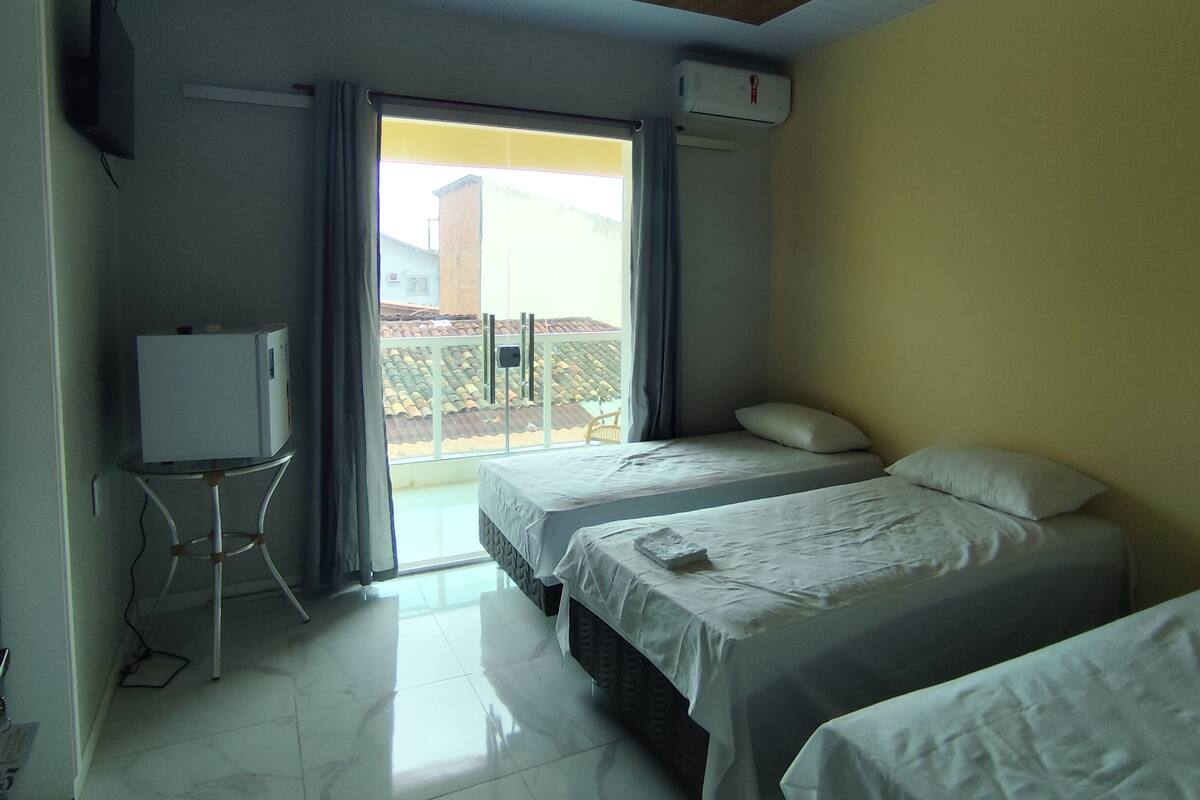 A hotel room with two beds, a TV, and a balcony with a view.