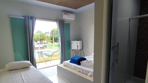 Ein Hotelzimmer mit Bett, einer kleinen Sitzecke mit Blick, einer Dusche und einem Fenster mit Vorhängen.