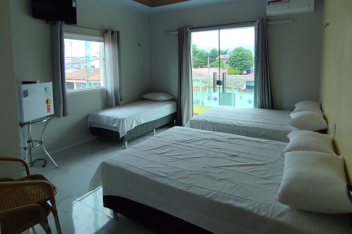 A hotel room with two beds, a television, and a view of the outside.