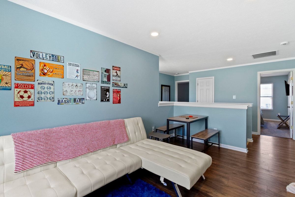 A living room with a sofa, a coffee table, and a wall decorated with sports memorabilia.
