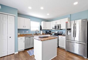 Een moderne keuken met witte kasten, roestvrijstalen apparatuur en een centraal eiland.