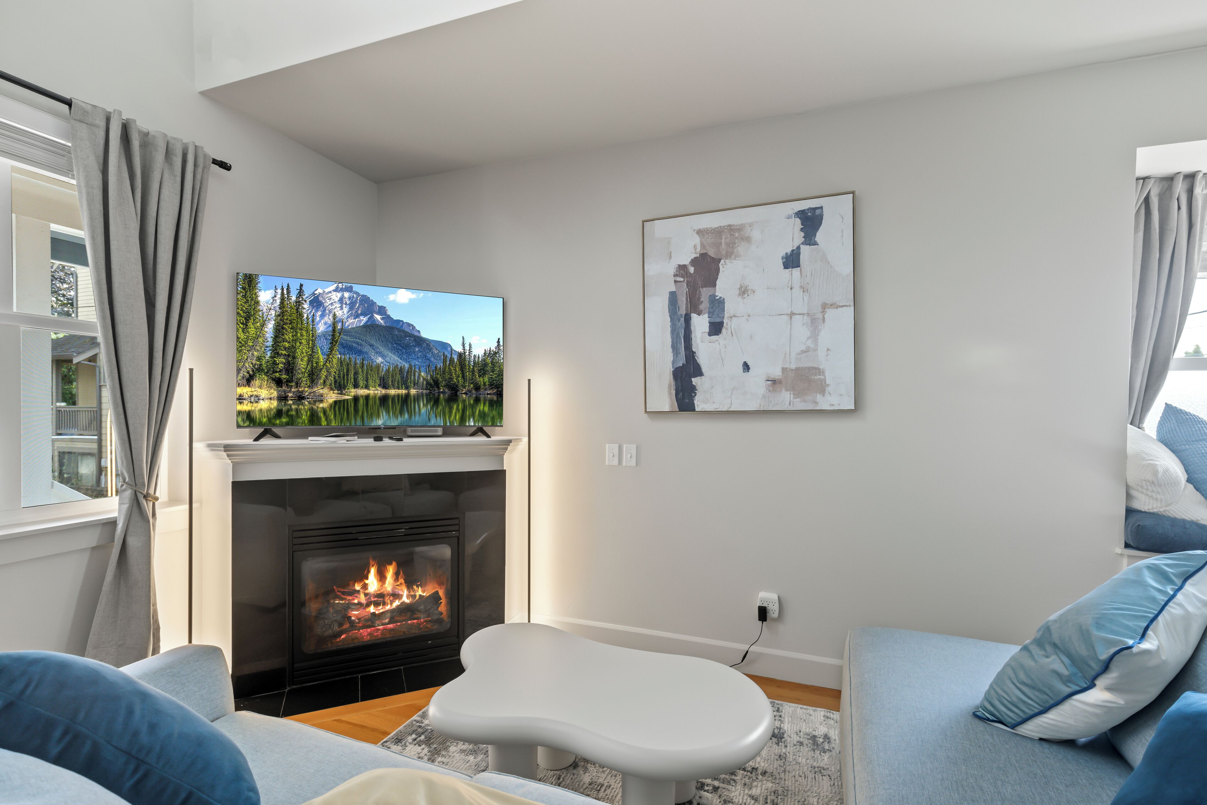 A modern living room with a fireplace, a flat-screen TV, and a cozy seating area.