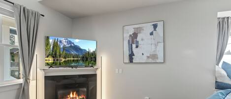 A modern living room with a fireplace, a flat-screen TV, and a cozy seating area.
