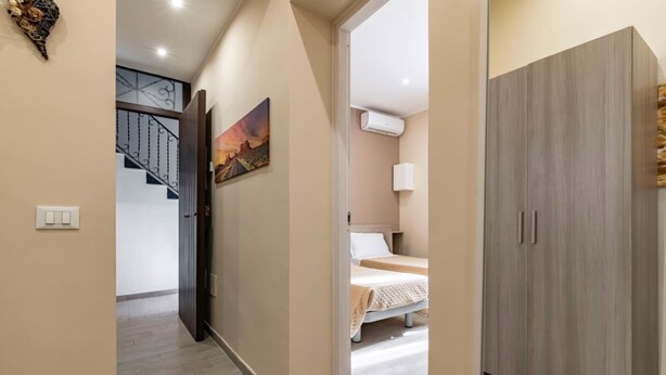 Un couloir avec un escalier, un lit avec une tête de lit et une armoire.