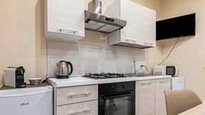 Une cuisine compacte équipée d’une cuisinière à gaz, d’un four, d’une machine à café et d’un four à micro-ondes.