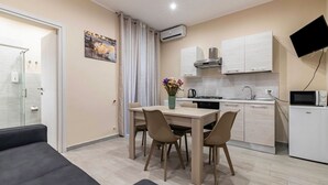 Une cuisine moderne avec une table et des chaises, un téléviseur fixé au mur et un petit réfrigérateur.