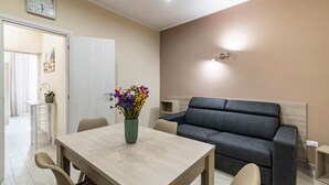 Un salon moderne avec une table à manger, un canapé et une horloge au mur.