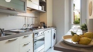 A modern kitchen with stainless steel appliances, white cabinetry, and a window with a view.