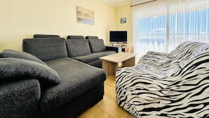 A living room with a sofa, a television, and a bed with a zebra print cover. - 2210 - MIRADOR II 55 WONDERFUL SEA VIEW, IDEAL SITUATION FOR HIKING, 150m. FROM THE BEACH OR FROM THE ROCKS. (Roses)