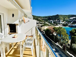 A balcony with a table and chairs, overlooking a coastal town with buildings and a beach. - 2210 - MIRADOR II 55 WONDERFUL SEA VIEW, IDEAL SITUATION FOR HIKING, 150m. FROM THE BEACH OR FROM THE ROCKS. (Roses)
