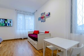 Une pièce avec un lit, une table et une fenêtre avec des rideaux.