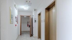 Ein Flur mit einer Tür, einem Feuerlöscher und einer Deckenleuchte.