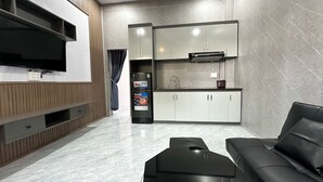 Een knus woongedeelte met een flatscreen televisie, een bank, een kitchenette met kastjes en een inbouwoven.