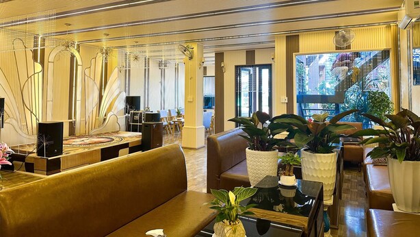Een moderne hotelentree met een zithoek, grote ramen en decoratieve planten.