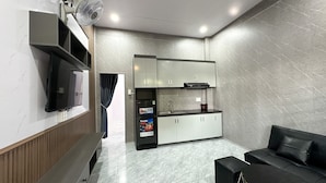 Een moderne keuken met inbouwapparatuur, een flatscreen-televisie en een zithoek met een zwarte bank.
