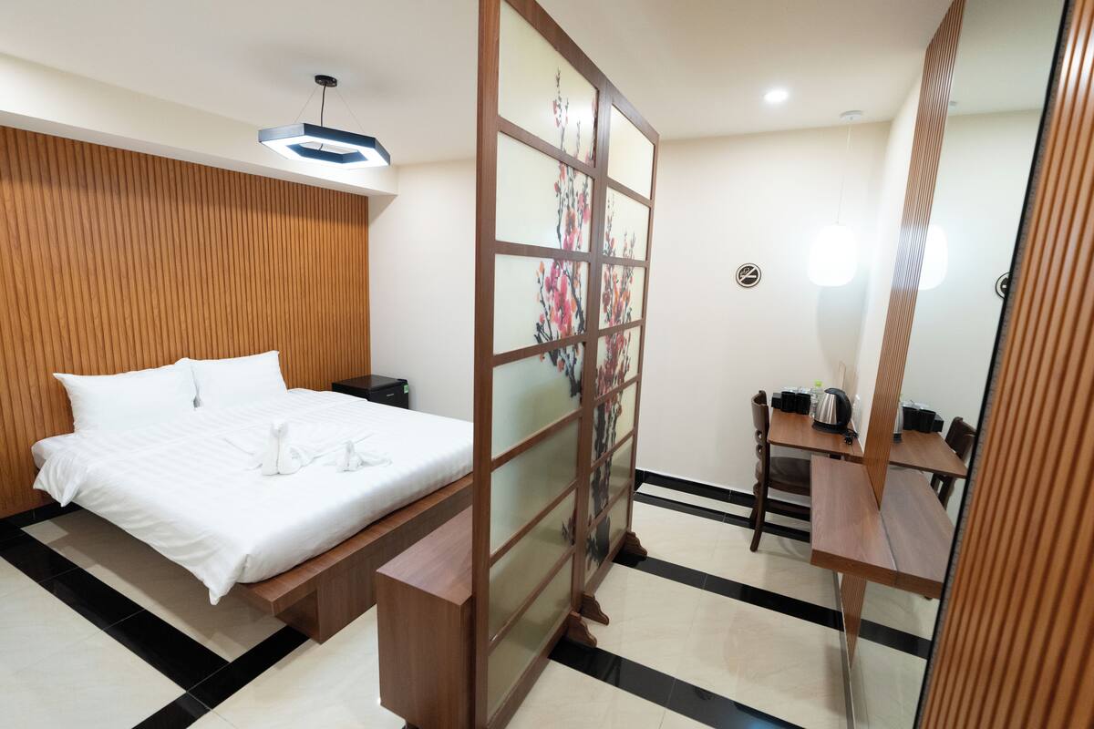 Une chambre d’hôtel avec un lit, une cloison en bois, un bureau et une chaise.