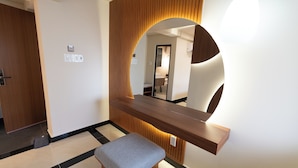 Un baño moderno con tocador de madera, un banco y un espejo grande.
